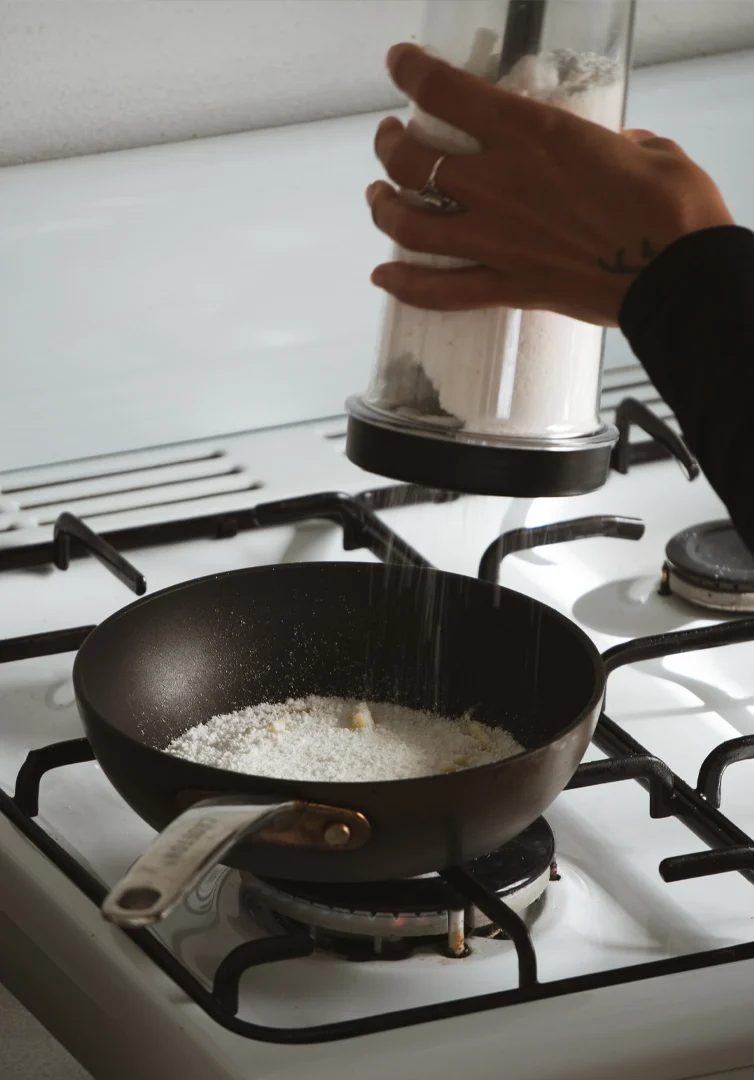 Sifting tapioca into a pan on the stove