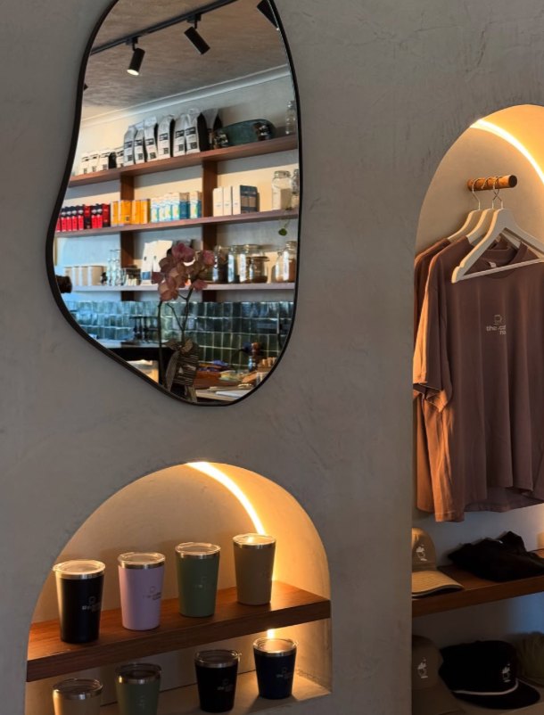 Keep cups and merch in lit arched niches beside a curved mirror