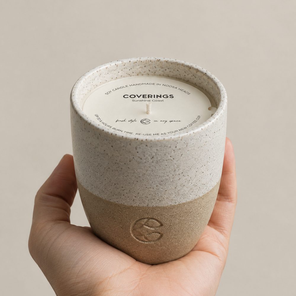 Coverings soy candle held in a hand