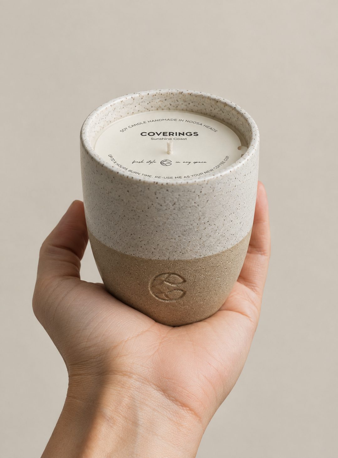Coverings soy candle held in a hand