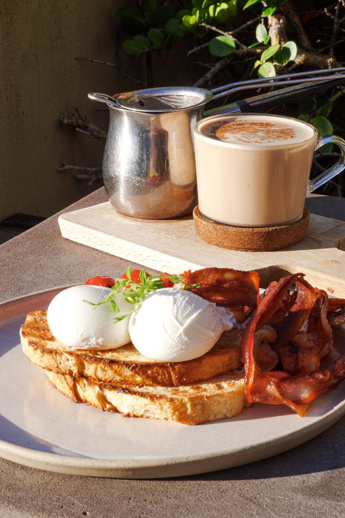 Poached eggs, bacon and a chai latte in the morning sun