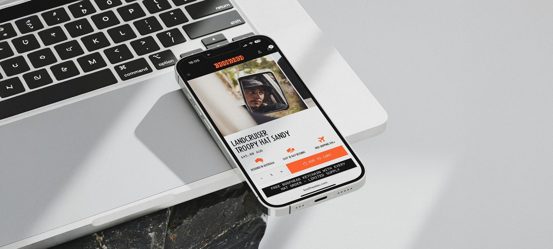 Boofhead online store product page on a phone resting on a laptop